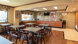 Un restaurante con mesas y sillas de madera, una zona de cocina con salpicadero de piedra y un reloj en la pared.