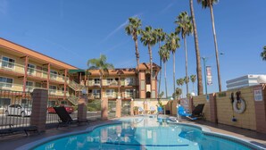 Un hotel con piscina, palmeras y un cielo azul despejado.