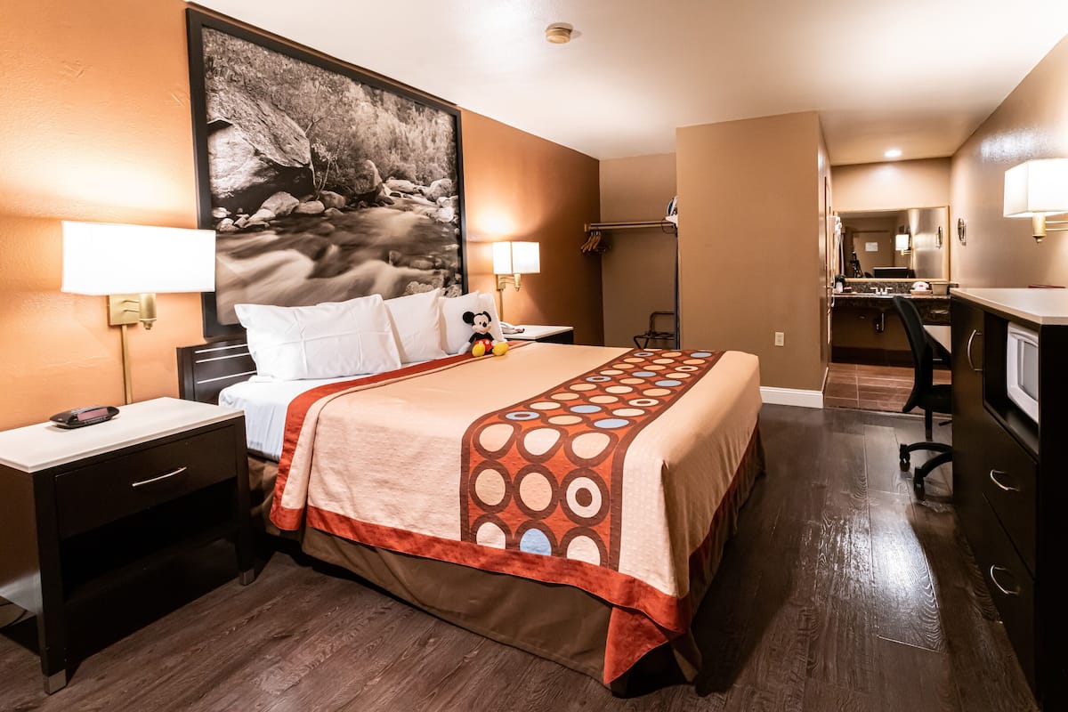 A hotel room with a bed, nightstands, a desk, and a large painting on the wall.