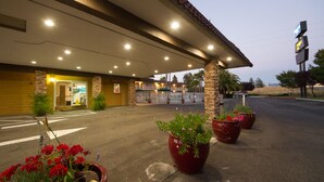 A hotel with a covered entrance, outdoor seating area, and potted plants. - Rodeway Inn Wine Country (Rohnert Park)