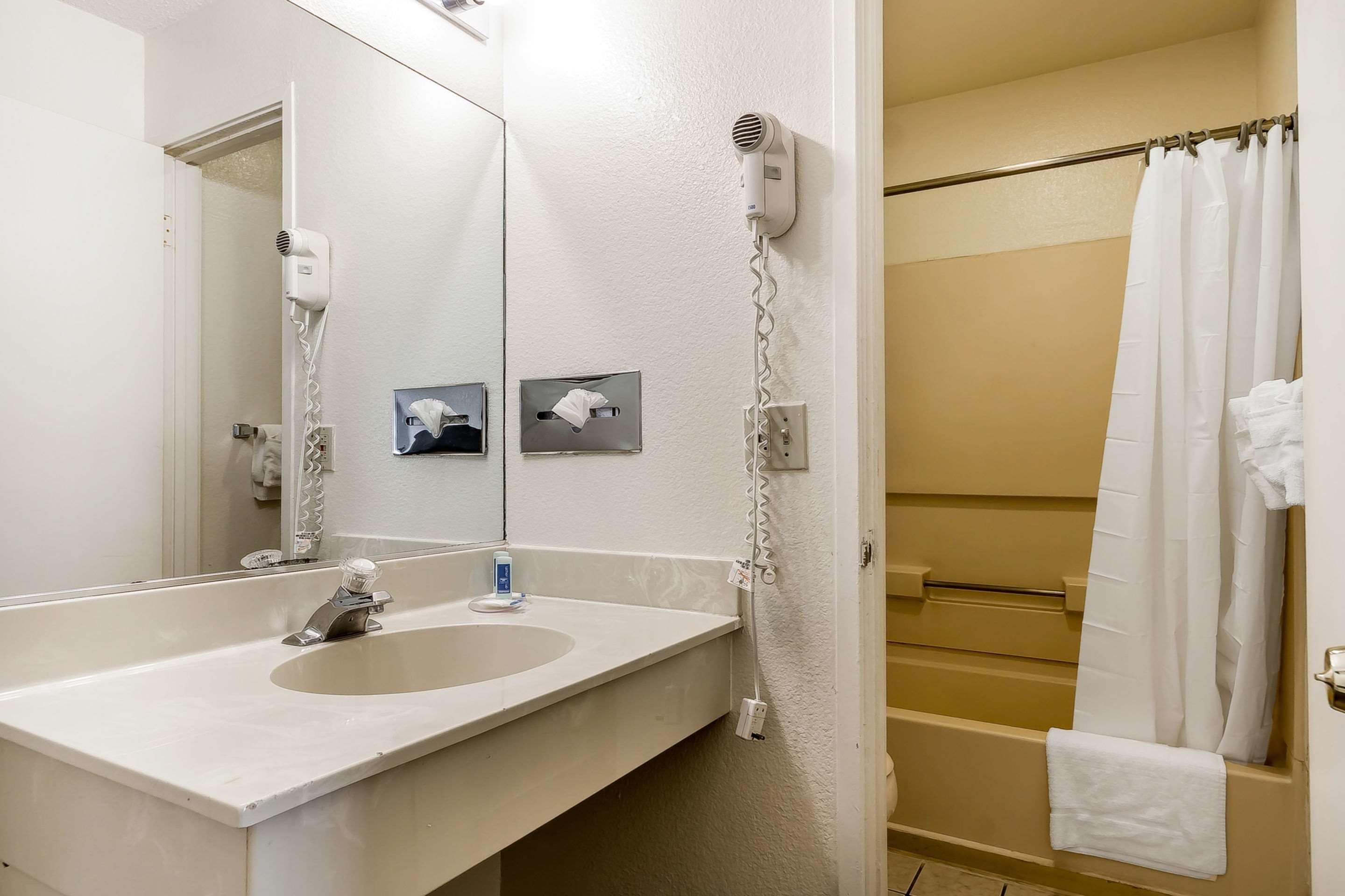 A bathroom with a sink, mirror, towel rack, and a shower curtain.