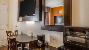 A hotel room with a flat-screen TV mounted on the wall, a coffee maker on the table, and a microwave. - Rodeway Inn Wine Country (Rohnert Park)
