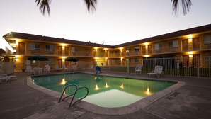 A hotel with a swimming pool, outdoor seating, and a fenced area. - Rodeway Inn Wine Country (Rohnert Park)