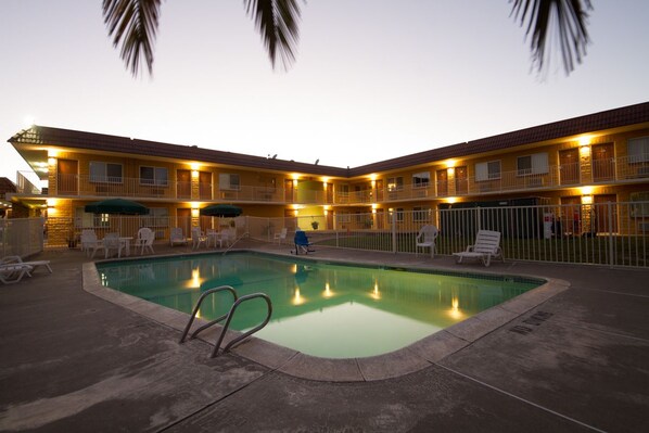 A hotel with a swimming pool, outdoor seating, and a fenced area. - Rodeway Inn Wine Country (Rohnert Park)