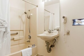 A bathroom with a bathtub, a shower, a sink, and a hairdryer.
