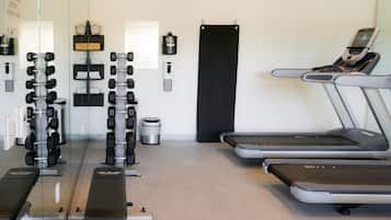 Un gimnasio con equipo de ejercicio, una cinta de correr y un cartel en la pared.