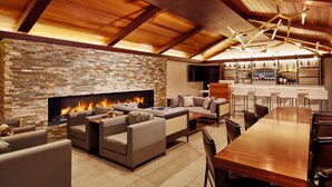 A modern living room with a stone wall, a fireplace, sofas, and a bar area with bottles. - The Nest Hotel Palo Alto (Palo Alto)