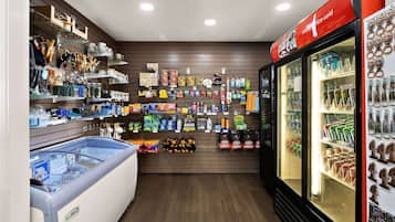 Una tienda con estanterías llenas de diversos productos, un mostrador refrigerado y un refrigerador Coca-Cola.