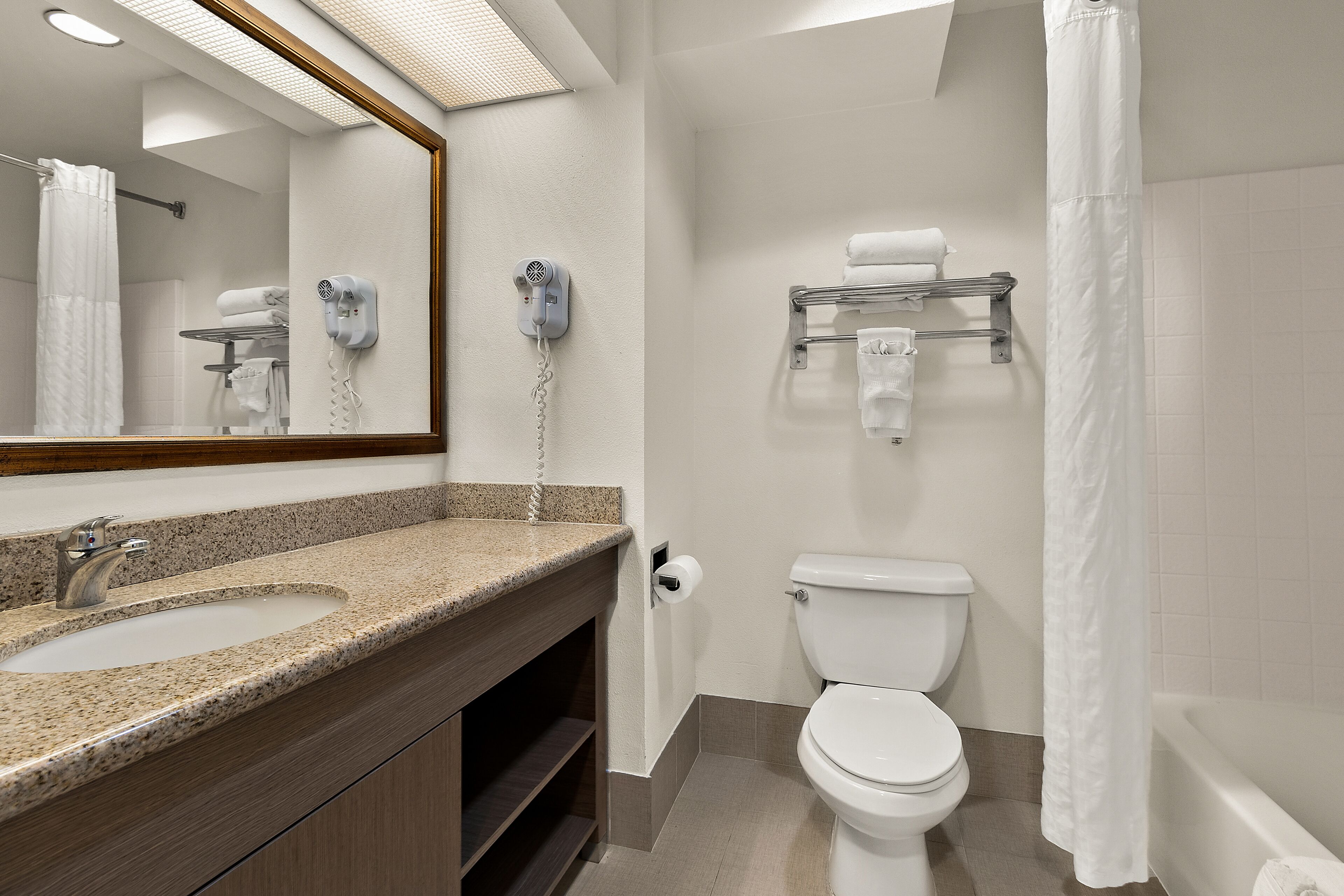 A bathroom with a sink, mirror, toilet, and shower curtain.