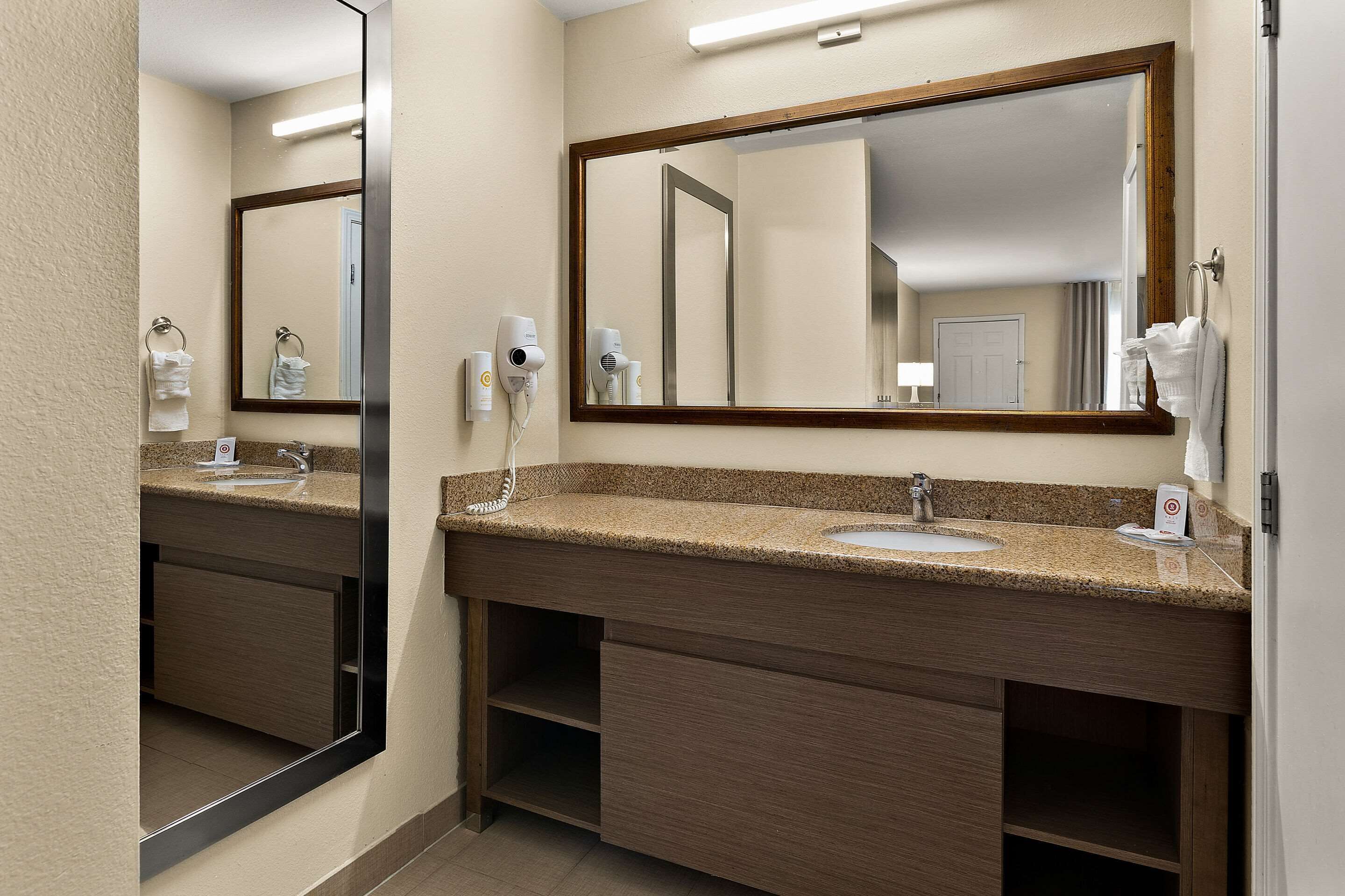 Une salle de bain d’hôtel avec un double vasque, un grand miroir et un sèche-cheveux.