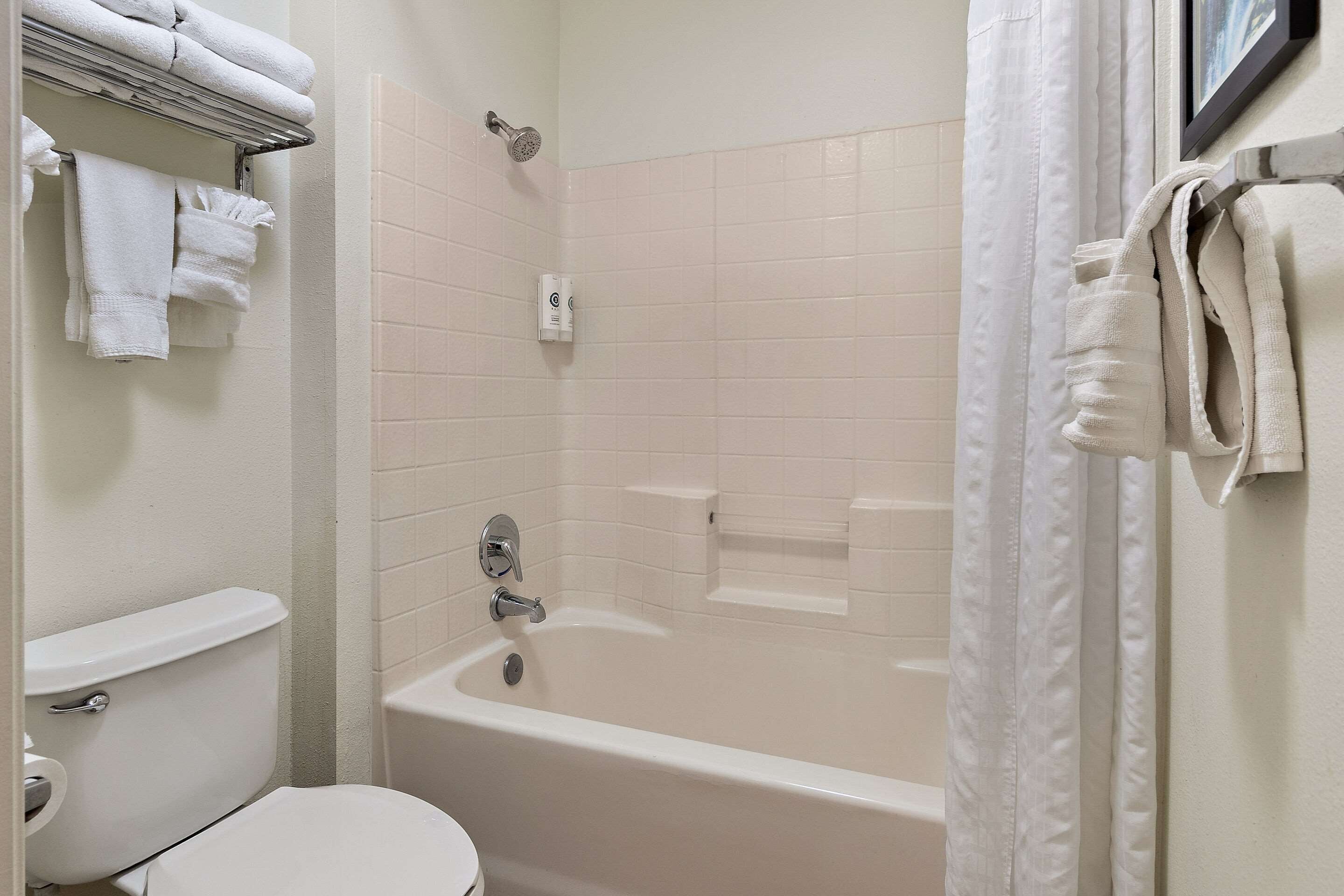 A bathroom with a bathtub, toilet, and towel rack.