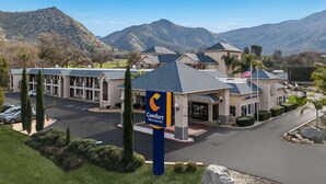A Comfort Inn & Suites hotel with a parking lot, a flag, and mountains in the background. - Comfort Inn & Suites Sequoia/Kings Canyon (Three Rivers)