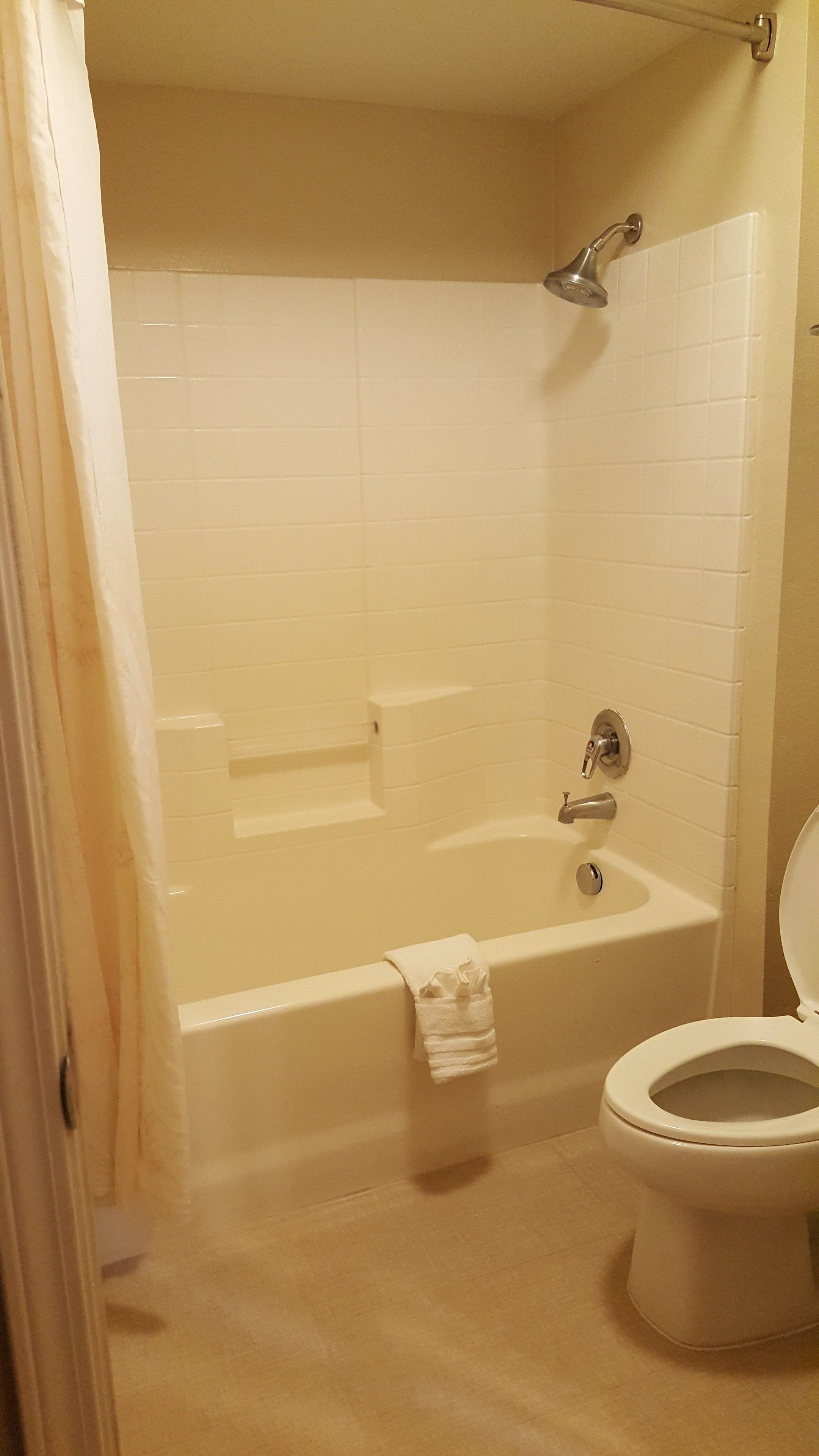 A bathroom with a bathtub, a toilet, and a showerhead.