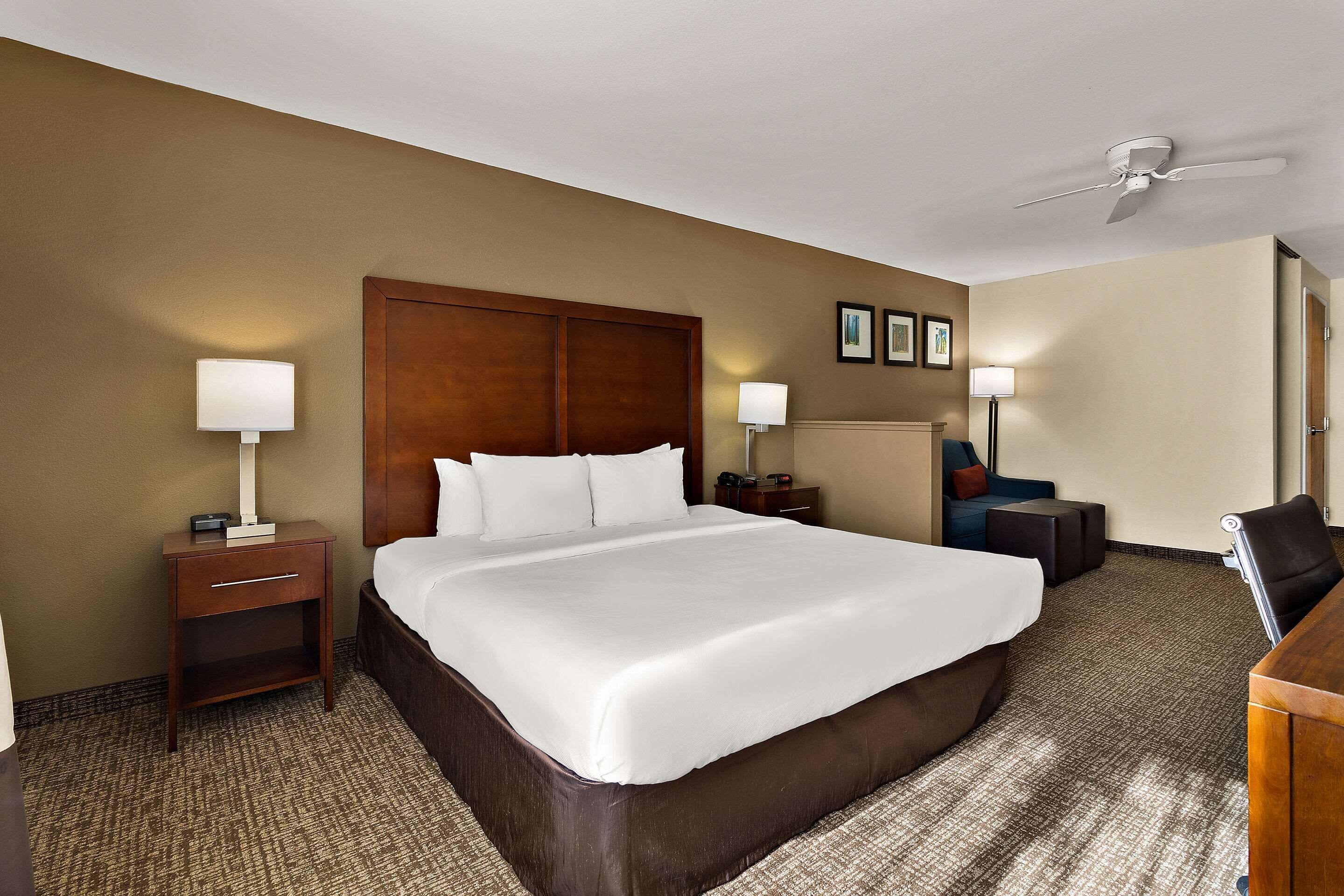 A hotel room with a large bed, two bedside tables with lamps, a desk, and a chair.
