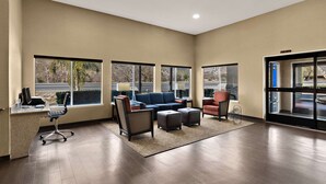 A spacious lobby with a blue sofa, armchairs, a desk with a computer, and large windows offering a view of the parking lot. - Comfort Inn & Suites Sequoia/Kings Canyon (Three Rivers)