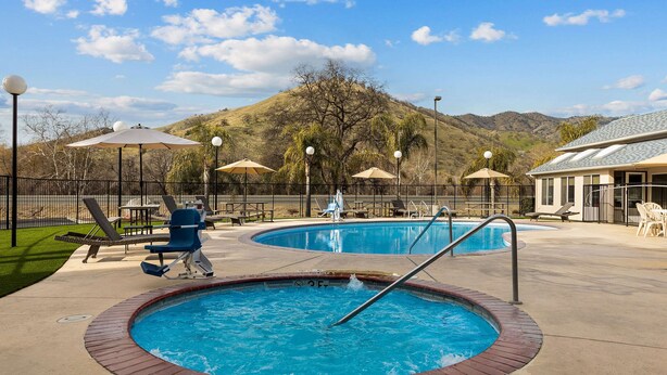 A pool area with two hot tubs, lounge chairs, umbrellas, and a view of hills. - Comfort Inn & Suites Sequoia/Kings Canyon (Three Rivers)