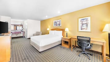 Una habitación de hotel con cama, escritorio, silla y televisor.