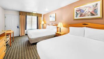 Une chambre d’hôtel avec deux lits, un bureau, une chaise, une commode et une fenêtre avec des rideaux.