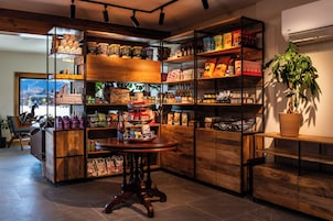 Un espacio comercial ordenado con estanterías llenas de diversos productos, una mesa de madera en el centro y una planta en maceta.