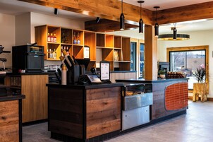 Un área de bar moderna con detalles de madera, una máquina de café y una pizarra con el menú.