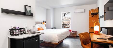 Une chambre d’hôtel avec un lit, un bureau, une chaise et une fenêtre.