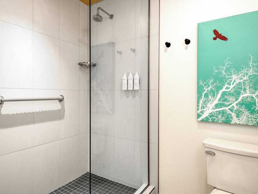 A bathroom with a glass shower enclosure, a toilet, and a wall-mounted sink.