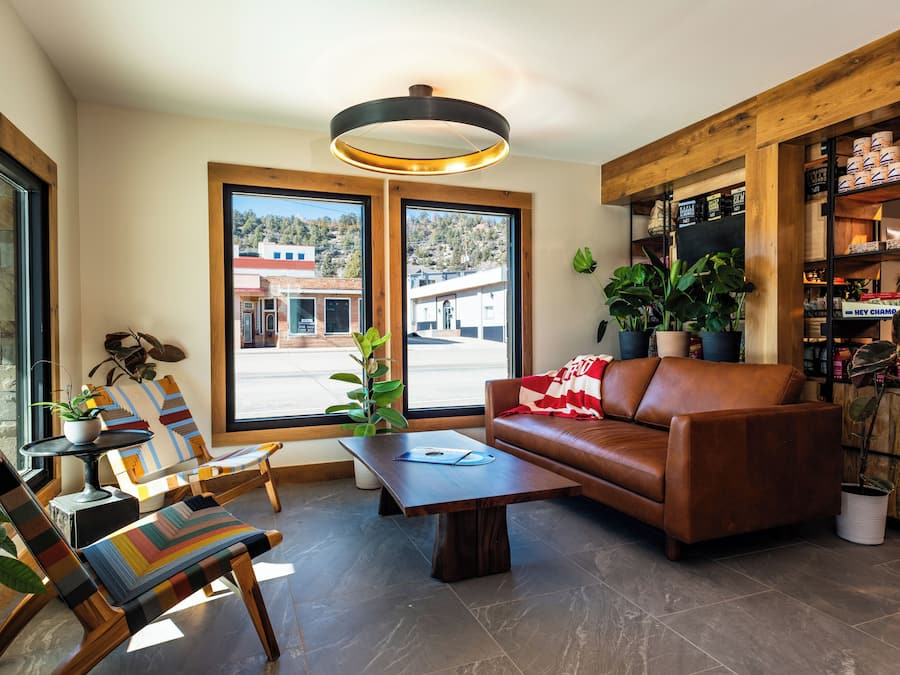 Una sala de estar moderna con un sofá de cuero marrón, sillas a rayas, una mesa de centro y una estantería de madera.