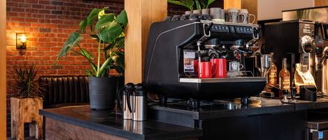 Une cuisine moderne avec une machine à café, des éléments en bois et un mur en briques.