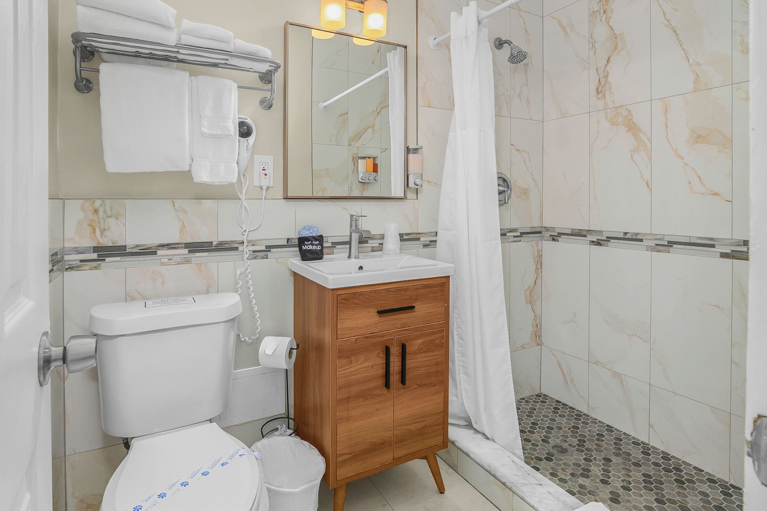 Une salle de bain comprenant des toilettes, un lavabo, un meuble-lavabo et un espace douche.