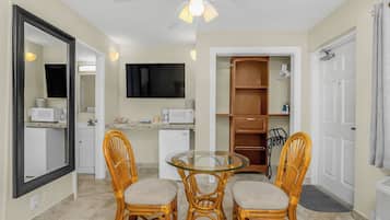 Espaço compacto com cozinha compacta, área de refeições com cadeiras de vime, TV de tela plana e closet espaçoso.