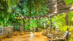 An outdoor seating area with wooden chairs and a pergola with string lights.