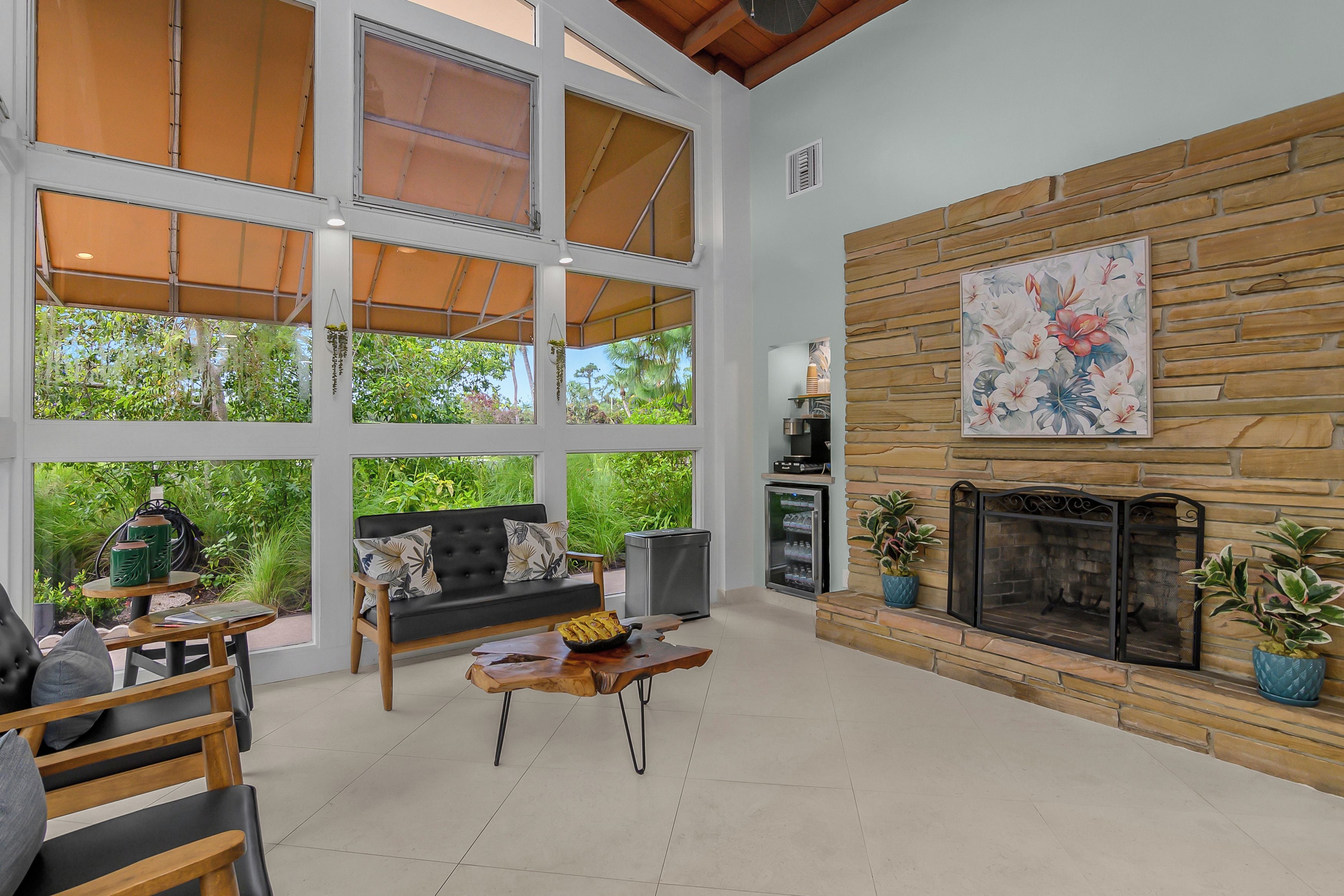A spacious living area with a fireplace, large windows, and a stone wall.