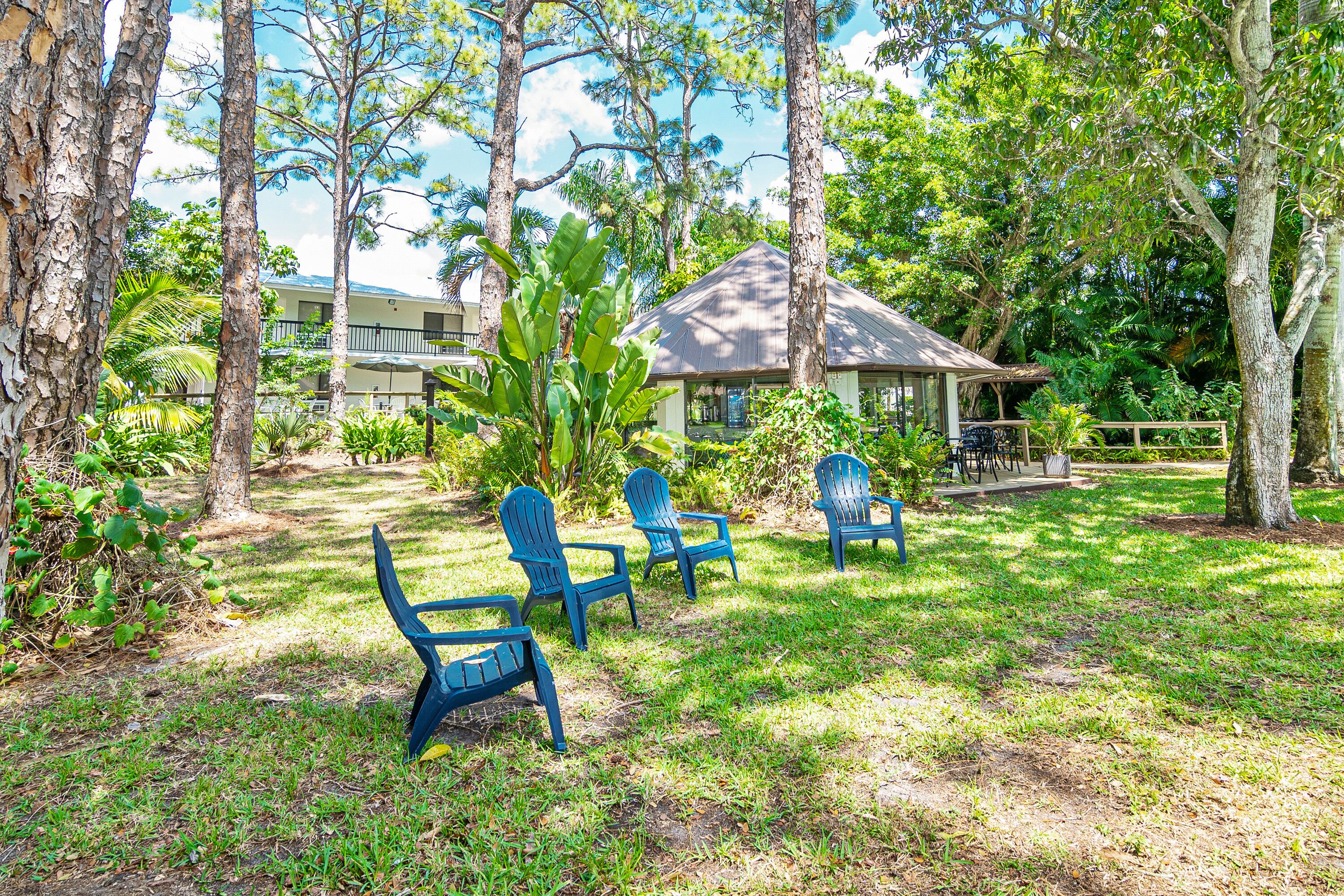 A grassy area with blue chairs and a small building with a sloped roof.
