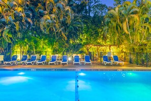 A swimming pool with lounge chairs and palm trees in the background.