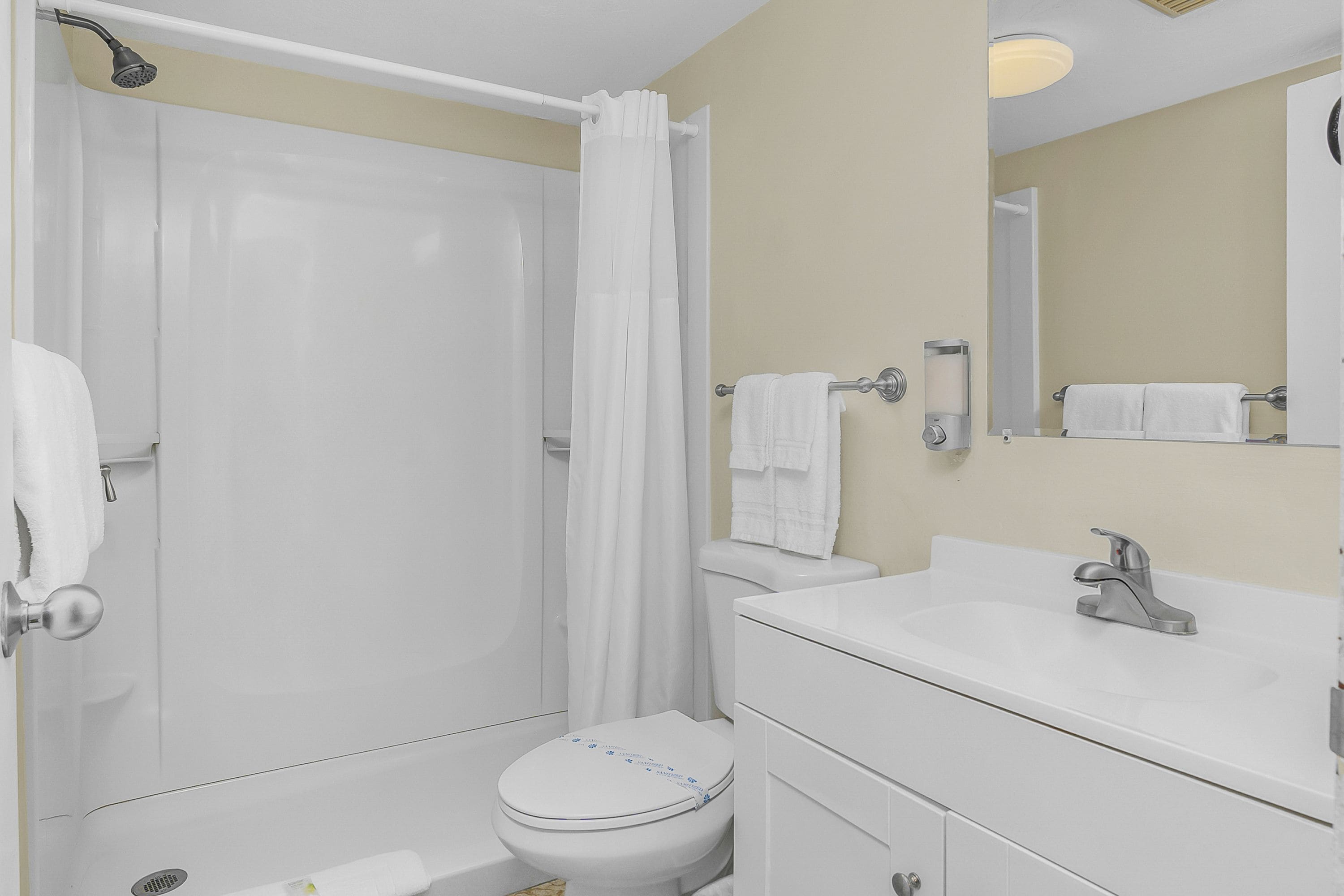 Une salle de bain équipée d’une douche, de toilettes, d’un lavabo et d’un miroir.