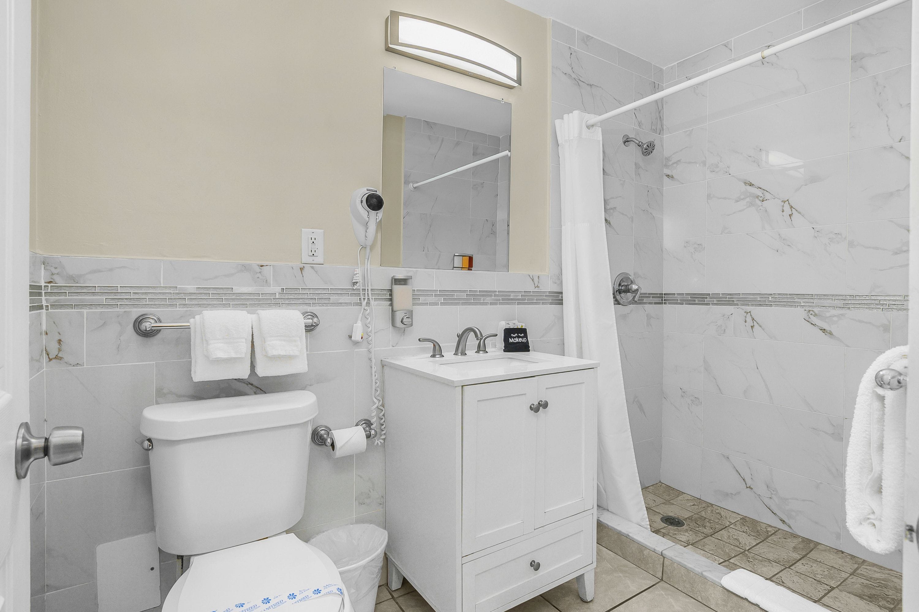 Baño con inodoro, lavamanos y zona de ducha.