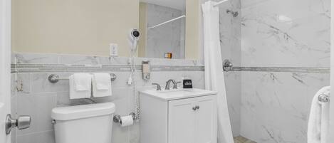 Baño con inodoro, lavamanos y zona de ducha.