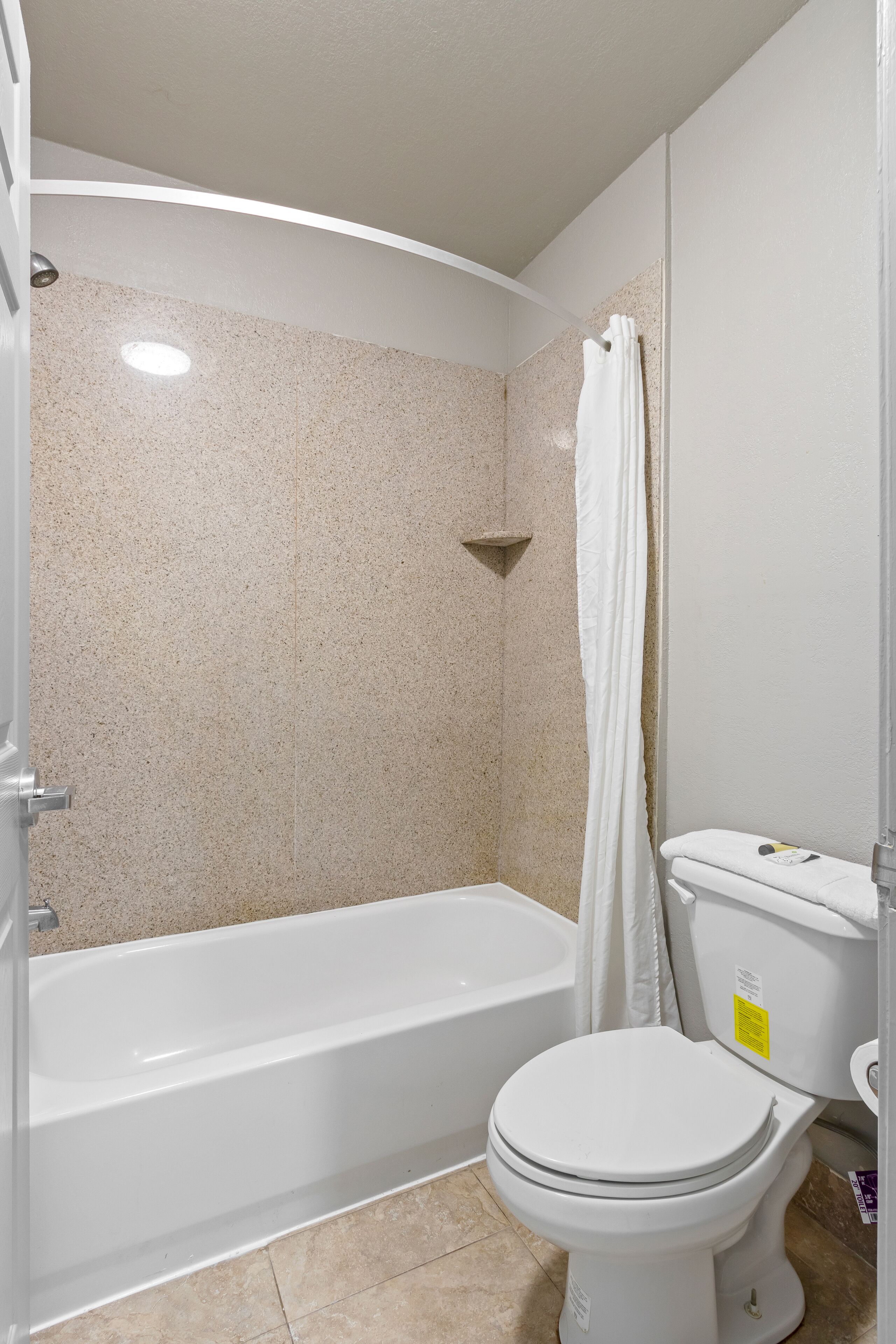 A bathroom with a bathtub, toilet, and shower curtain.
