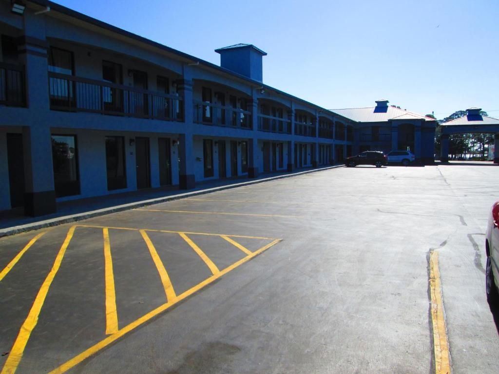 A parking lot with marked spaces and a building with multiple balconies.