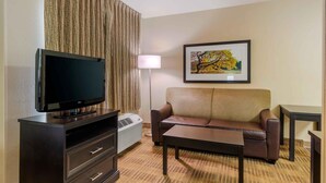 A hotel room with a flat-screen TV, a sofa, a coffee table, a lamp, and a framed picture on the wall. - Extended Stay America Select Suites Atlanta Buckhead (Atlanta)