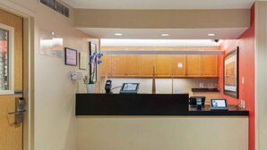 A reception area with a black counter, wooden cabinets, a framed picture, and a potted plant. - Extended Stay America Select Suites Atlanta Buckhead (Atlanta)