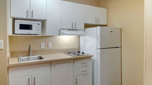 A kitchen with white cabinets, a microwave, a stove, a sink, and a refrigerator. - Extended Stay America Select Suites Atlanta Buckhead (Atlanta)