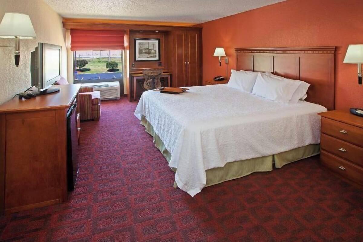 A hotel room with a bed, a desk, a chair, a television, and a window with a view.