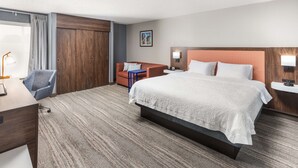 A hotel room with a large bed, a desk, a chair, a wardrobe, and a painting on the wall. - Hampton Inn Joliet-Plainfield I-55 (Joliet)