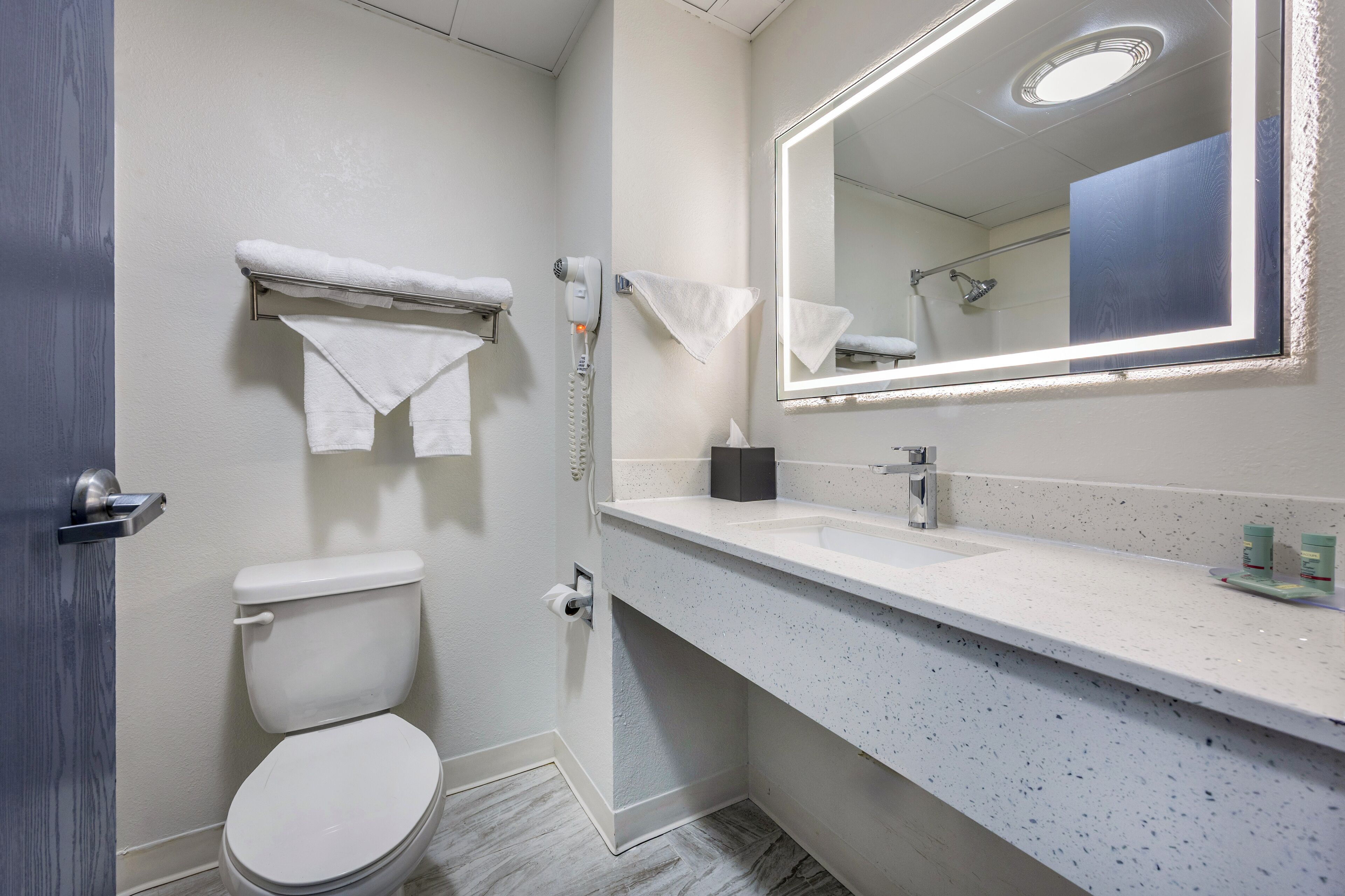 Een moderne badkamer met een wit toilet, een wastafel met spiegel en een handdoekrek.