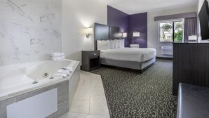 A modern hotel room with a large bed, a separate bathroom with a bathtub, and a view of the outdoors through a window. - Best Western Bolingbrook Hotel (Bolingbrook)