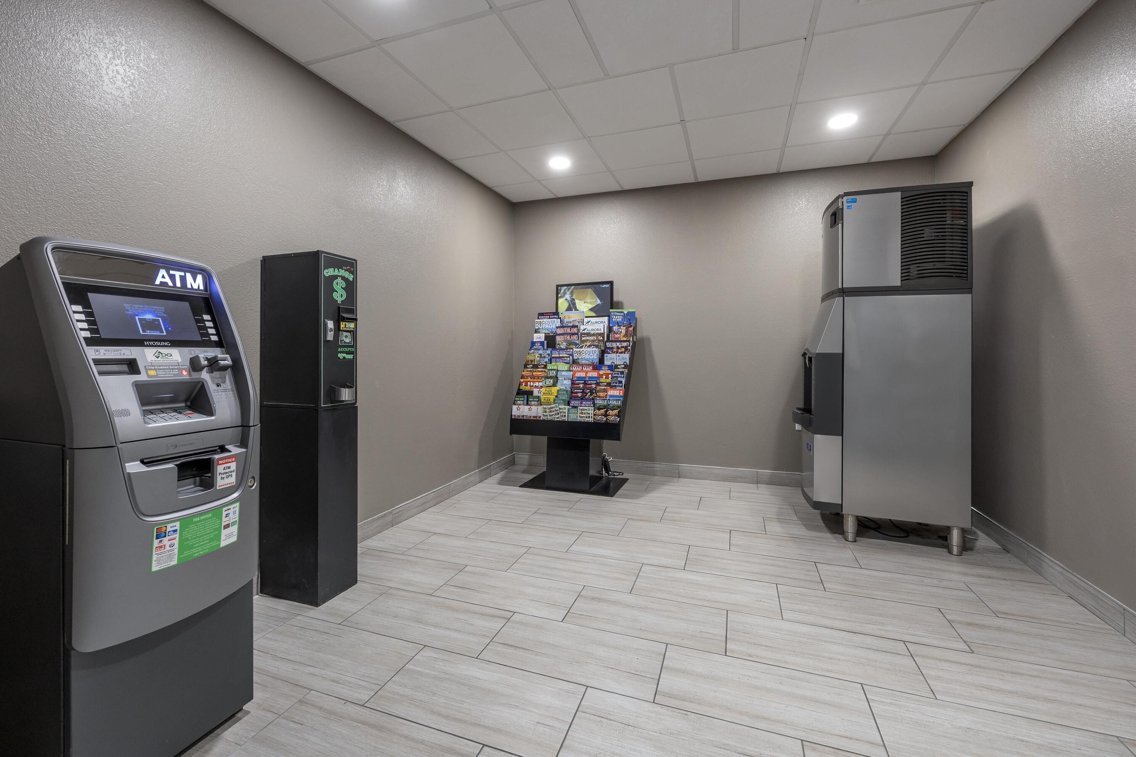 An ATM, a vending machine, and a refrigerator in a room with tiled flooring and a plain wall.