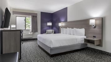 A modern hotel room with a large bed, a desk, and a flat-screen TV.