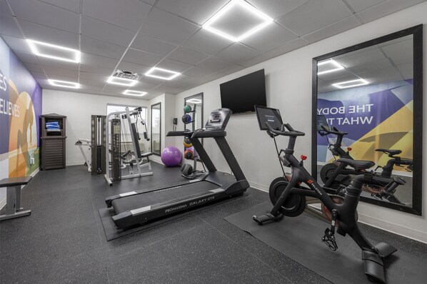 A gym with treadmills, stationary bikes, and exercise balls.