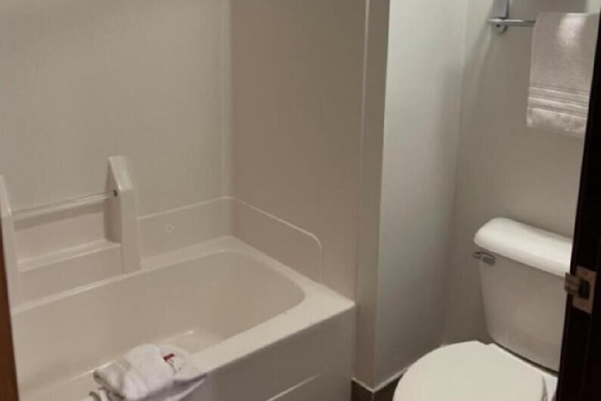 A bathroom with a bathtub, toilet, and a towel rack.